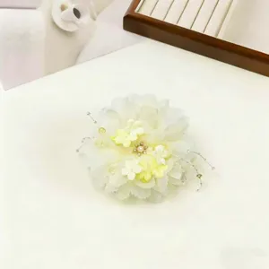 Detail view of the elegant white fabric flower hair clip, featuring delicate pearls and beads.
