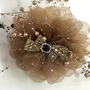 Close-up detail of the brown mesh flower hair claw clip with rhinestones and pearl tassels.