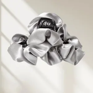 Detailed close-up showing the smooth silver satin texture and delicate pleates of the hair claw clip.