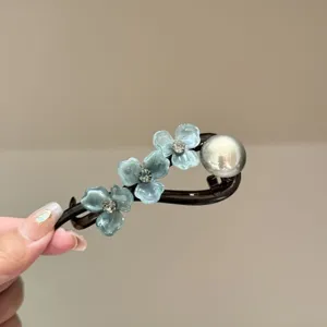 Close-up detail of vintage blue acetate flower hair clip with rhinestones and elegant pearl.