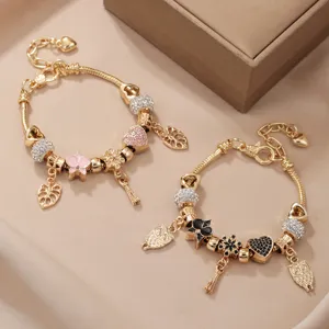 Gros plan de bracelets charms plaqués or avec strass scintillants et pendentifs émail.