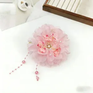 Detail view of pink floral hair claw with delicate pearl tassels, elegant accessory for hairstyles.