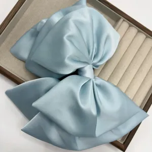 Elegant light blue satin bow hair clip for women, stylish ponytail holder accessory.