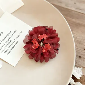 Exquisite red fabric flower hair accessory detail, elegant floral design for styling.