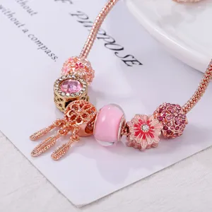 Rose goudkleurige bedelarmband detail met roze dromenvanger hanger en mooie kralen.