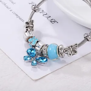 Gros plan détaillé du bracelet en acier titane argenté avec papillons cristal bleu.