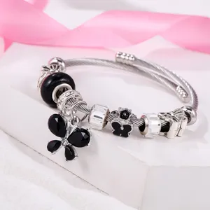 Gros plan détaillé du bracelet breloque argenté avec pendentif papillon noir et strass.
