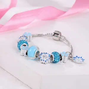 Close-up details van zilveren slangketting bedelarmband met blauwe kristallen en madeliefjes.