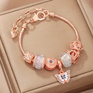 Rose gold charm bracelet detail shot featuring a sparkling butterfly pendant and decorative beads.