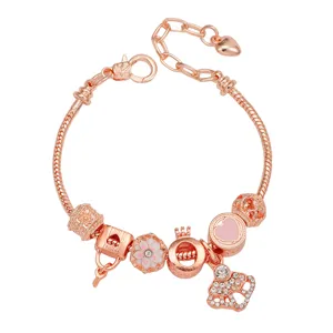 Détail de bracelet charm en or rose avec cadenas d'amour et breloques florales femme.