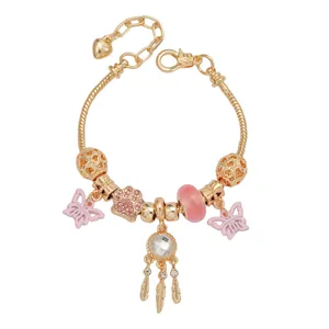 Detailopname van de gouden bedelarmband met roze vlinder, pootafdruk en dromenvangerhangers.