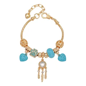 Gouden charm armband detail met een opvallende dromenvanger en heldere blauwe hartjes.