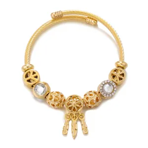 Close-up detail of gold-plated stainless steel charm bracelet with dreamcatcher pendant.