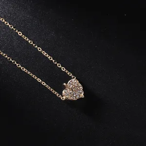 Vue détaillée d'un collier pendentif feuille dorée délicat, orné de cristaux de strass.