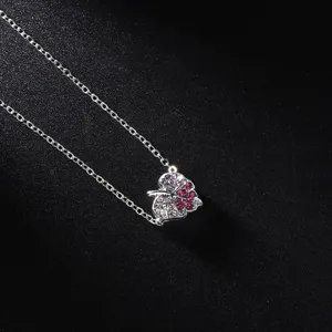Gros plan détaillé d'un collier pendentif feuille argenté orné de cristaux multicolores.