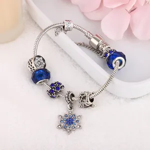 Blue crystal charm bracelet detail, silver snake chain with sparkling snow flower pendant.