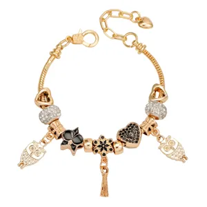 Bracelet charms doré avec pendentifs hibou et cœur, accessoire de mode élégant.