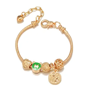 Detail view of gold-plated snake chain charm bracelet with constellation pendant and beads.