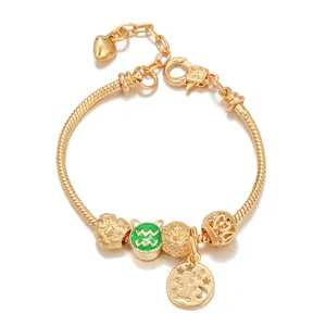 Gold snake chain charm bracelet detail featuring Aquarius green enamel bead and constellation pendant.
