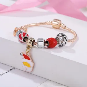 Détail de bracelet à breloques de Noël avec pendentif Père Noël et perles rouges élégantes.