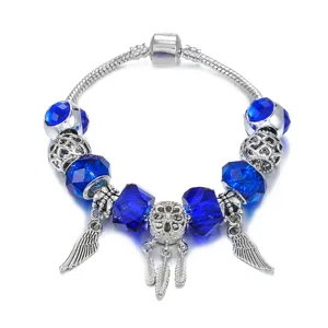 Pulsera de abalorios plateada con cuentas de cristal azul, dijes de alas y colgante atrapasueños.