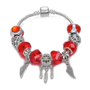 Vista detallada del pulsera de dijes plateada con cuentas de cristal rojo y dijes de plumas.