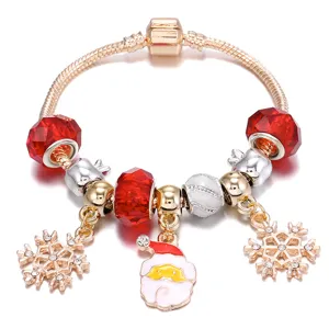 Vista dettagliata di un bracciale con ciondoli natalizi in oro rosa e perline di vetro rosso.