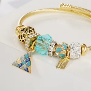 Goldener Charm Armband Detailaufnahme mit blauem Mosaik Anhänger und Kristallperlen.