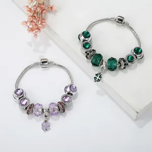 Detailed view of DIY charm bracelets featuring green and purple crystals with clover dangles.