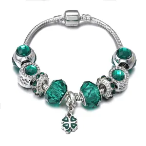 Close-up of silver charm bracelet with green crystal beads and cute clover pendant detail.