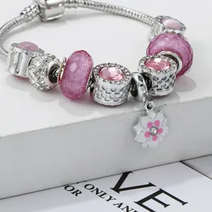 Nahaufnahme des silbernen Bettelarmbands mit funkelnden rosa Glasperlen und Blumenanhänger.