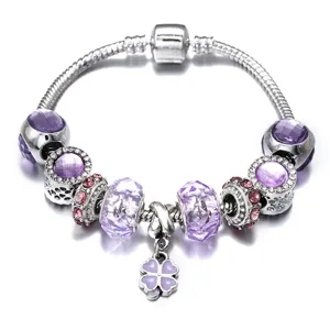 Detailed view of silver snake chain charm bracelet with purple crystal beads and clover pendant.