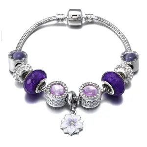 Nahaufnahme des silbernen Schlangenkette-Charm-Armbands mit violetten facettierten Perlen.