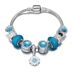 Modischer DIY Silber Bettelarmband mit blauen Glasperlen und weißem Gänseblümchen Anhänger.