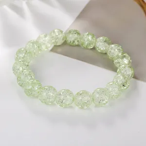 Close-up detail of light green crackle crystal beaded bracelet, elegant crack texture details.