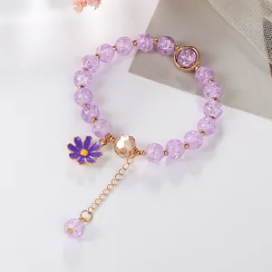 Purple cracked crystal bracelet detail, golden metal elements, cute daisy charm design.