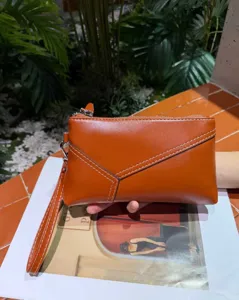 Brown genuine leather women clutch bag featuring geometric stitching and a convenient wrist strap.
