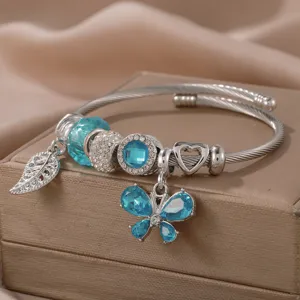 Stainless steel cable charm bracelet with blue crystal beads, butterfly and leaf pendants.