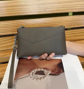 Grey leather wristlet clutch bag for women, featuring a secure zipper and handy strap.