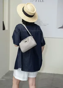 Detailed view of a stylish light grey genuine leather shoulder bag with chic metal turn lock.