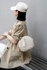 Minimalist round leather crossbody bag for women, stylish vintage shoulder bag with strap.