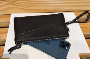 Genuine leather black wristlet clutch detail showing phone capacity and fine stitching.