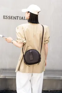 Detail view of the retro genuine leather round crossbody bag, showing fine texture and strap.