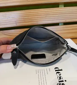 Detailed view of black genuine leather clutch interior with zipper and card slots inside.