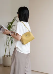 Detailed shot of yellow genuine leather underarm bag worn by model, chic everyday fashion style.