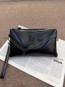 Close-up detail of a black genuine leather clutch bag, featuring contrast stitching and wrist strap.