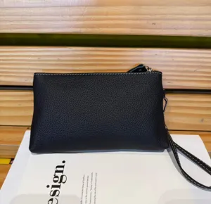 Black leather clutch bag detail shot, featuring zipper closure and convenient wrist strap.