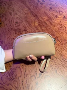 Detailed close-up view of the minimalist leather clutch bag, showing texture and wrist strap.