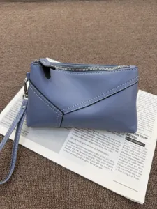 Blue leather wristlet clutch bag detail view featuring silver zipper and convenient wrist strap.