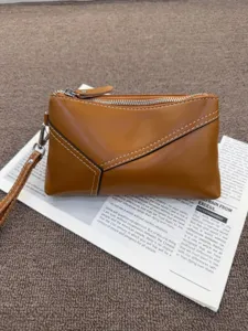 Detail view of the vintage brown genuine leather clutch bag with contrast stitching and strap.